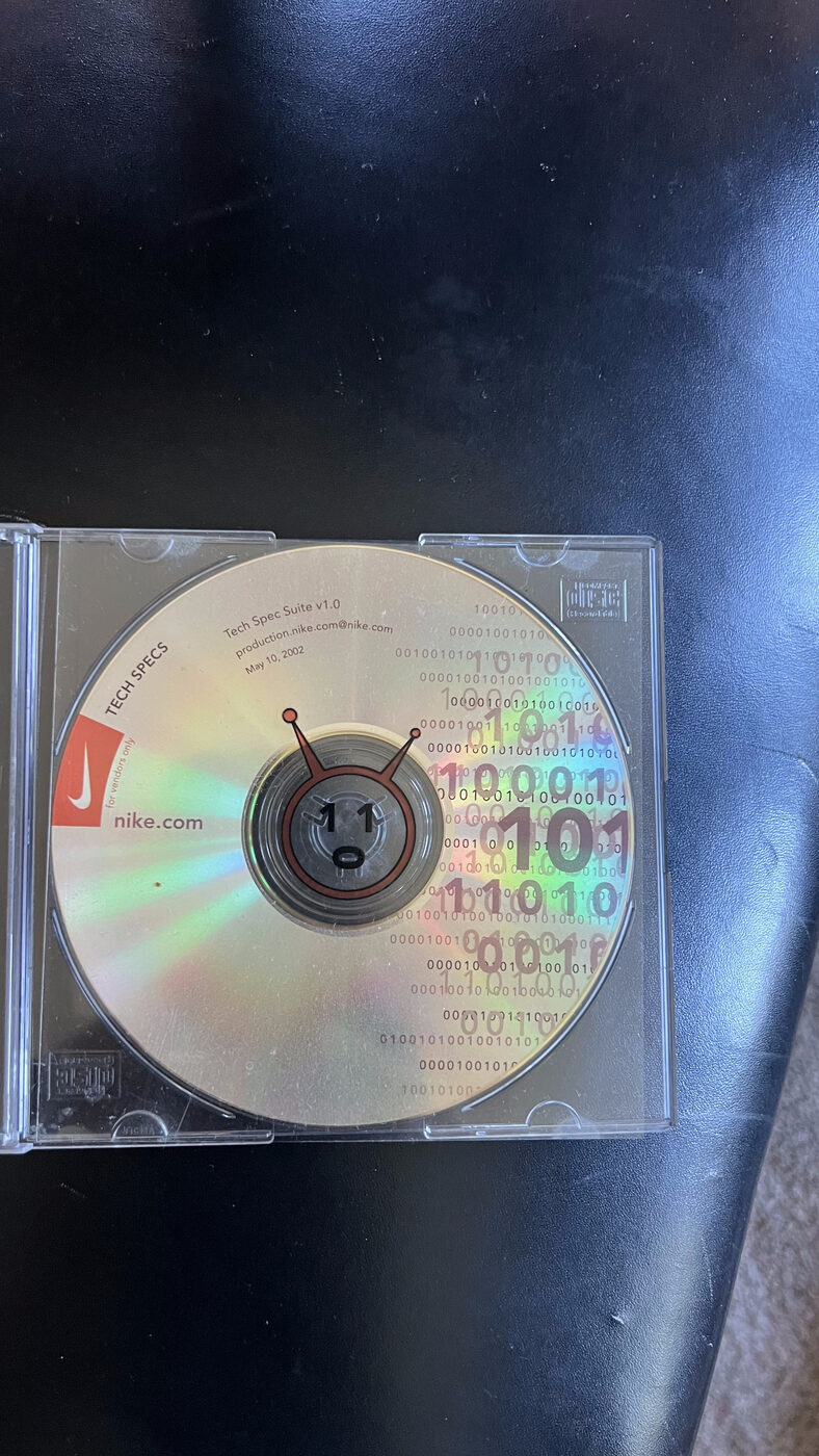 Close-up of the nike.com Tech Specs CD showing the binary-code artwork and a small robot face printed on the hub